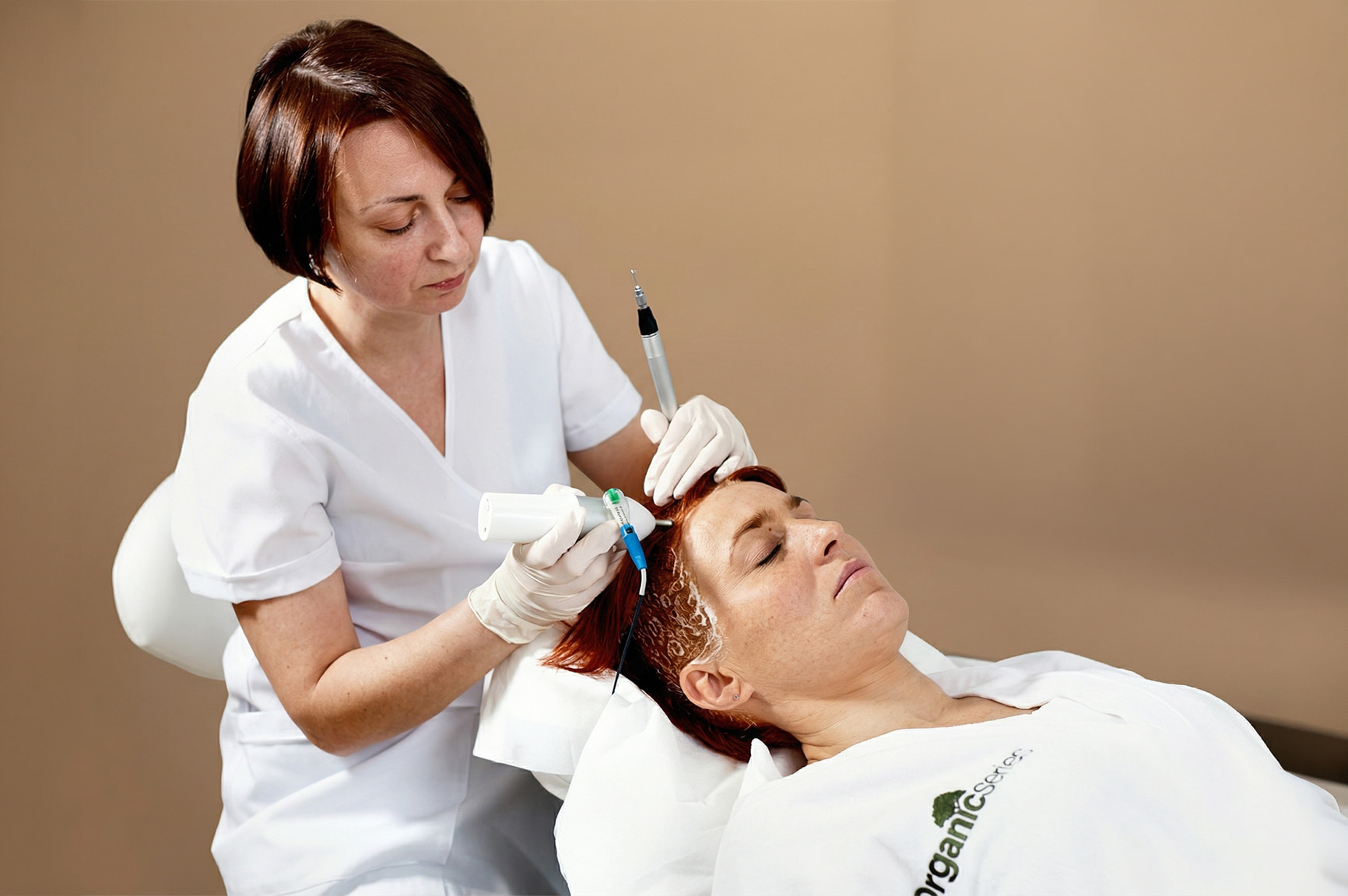 Specjalistka trycholog w&nbsp;białym uniformie wykonuje badanie skóry głowy pacjentki za&nbsp;pomocą specjalistycznego sprzętu w&nbsp;gabinecie Kliniki Włosa Rokoko.