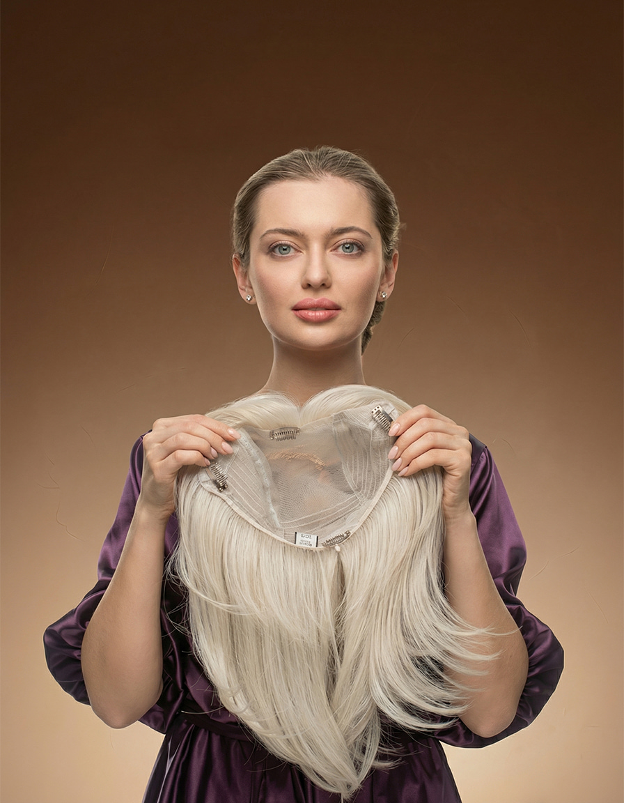 Kobieta w&nbsp;fioletowej bluzce prezentuje jasny topper blond, trzymając go obiema dłońmi od&nbsp;spodu na&nbsp;beżowym tle.